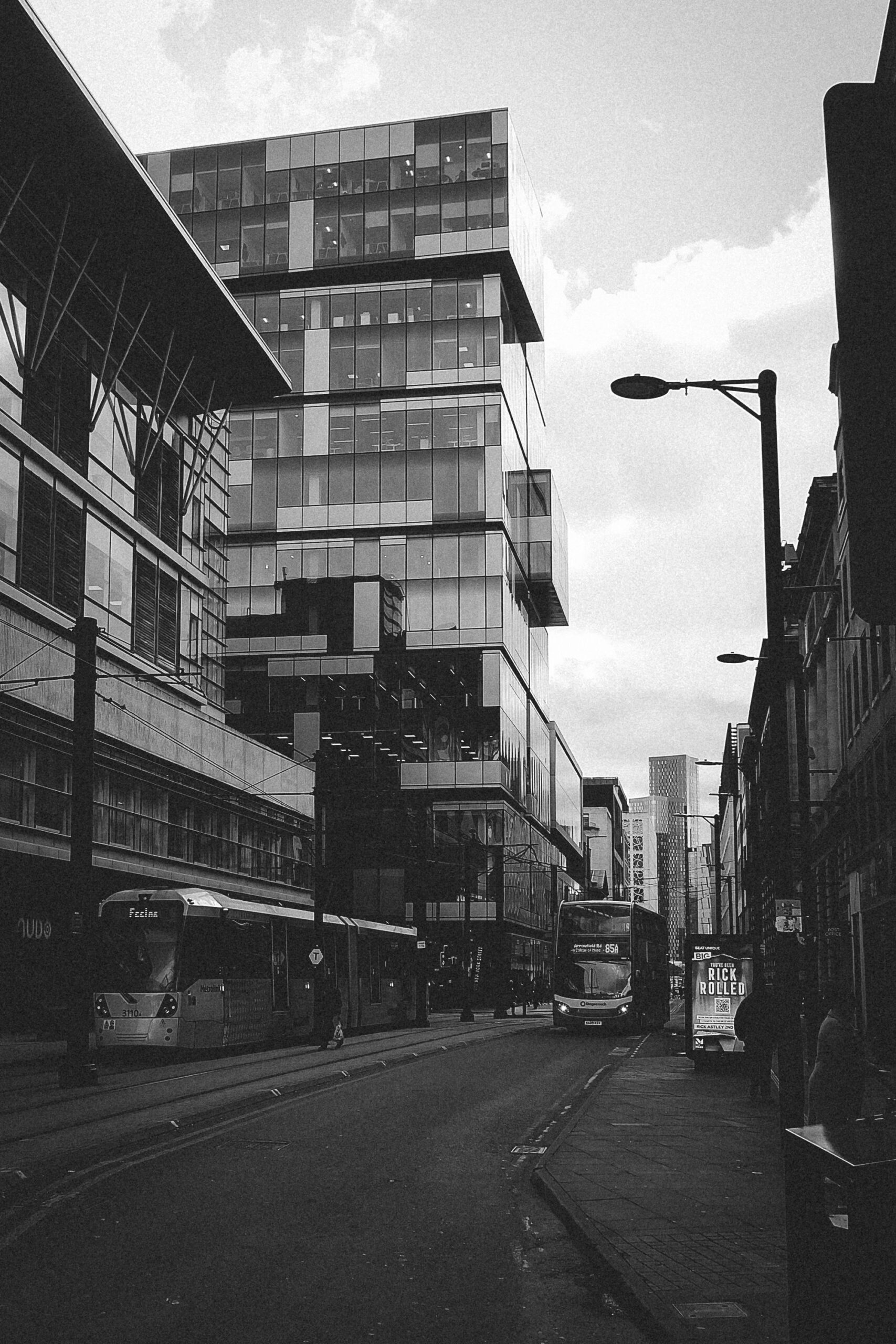 Black and white view of Manchester architecture, glass and concrete facades meeting an overcast sky.