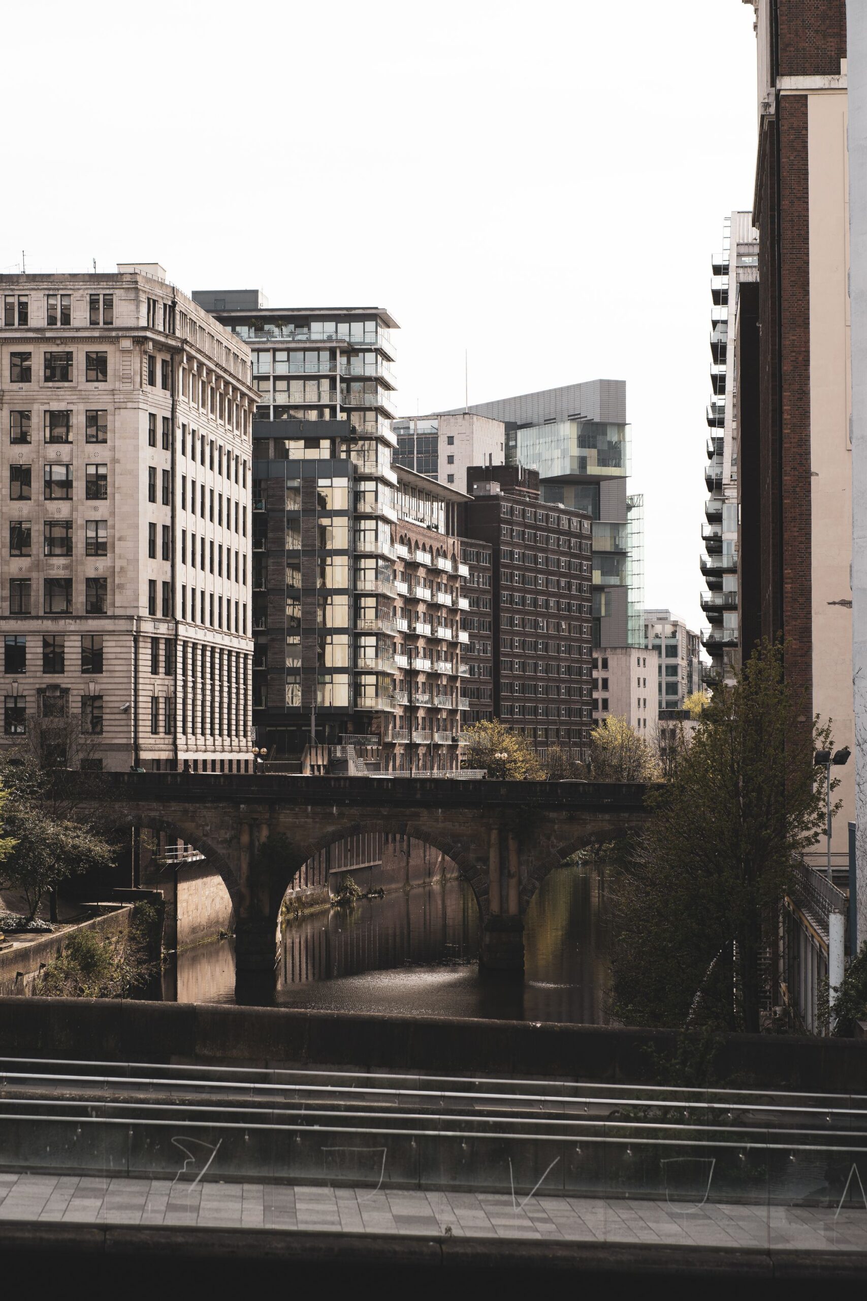 Manchester city centre, with new residential towers rising behind the brick arches of a Victorian railway viaduct.